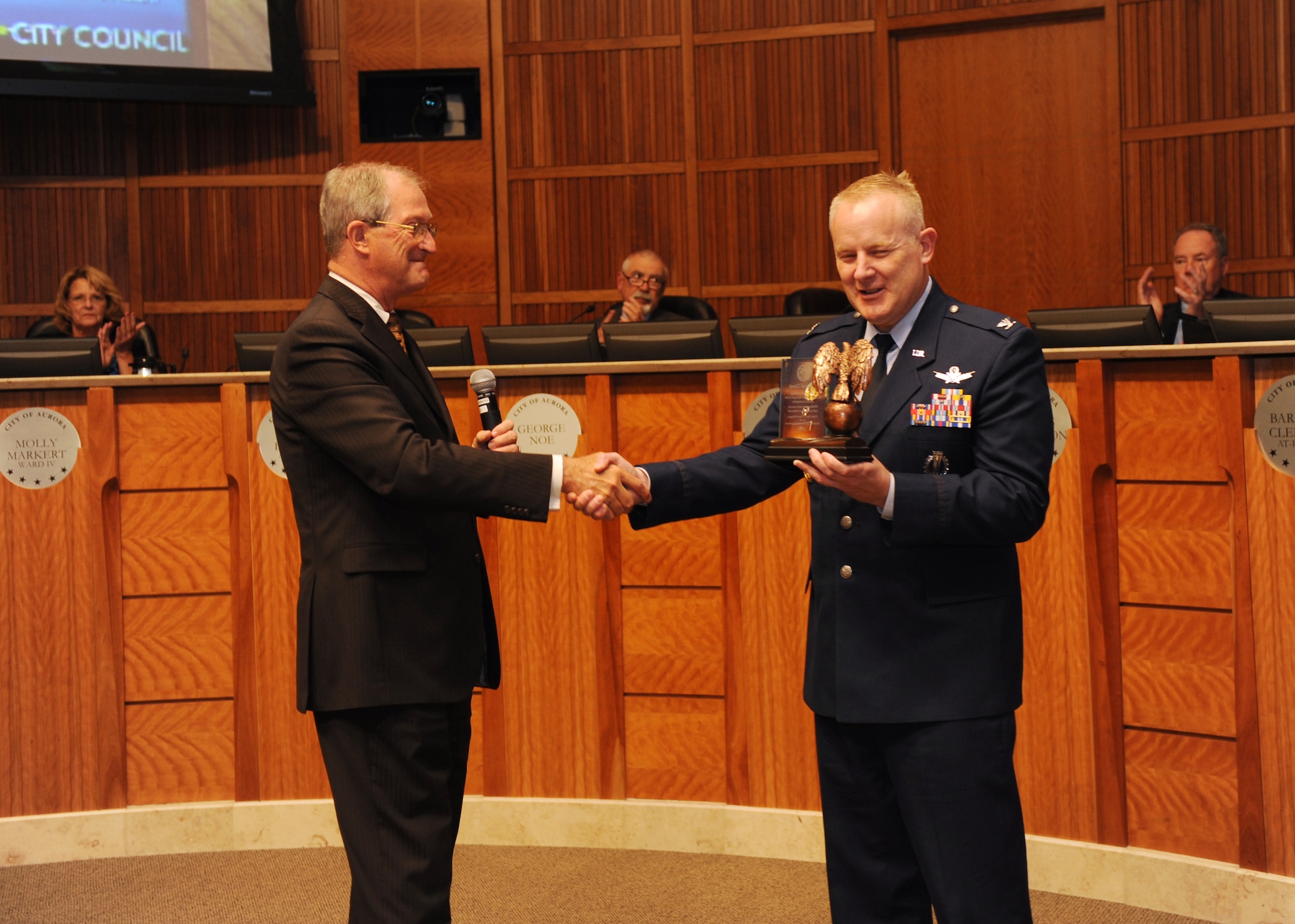 Col. Dan Dant, 460th Space Wing commander, receives an award from Aurora Mayor Steve Hogan and the Aurora City Council members, June 3, 2013, at the Aurora Municipal Center, Colo. The mayor presented Dant with an award, thanking him for his time and dedication to the community and wished him luck on his upcoming assignment. (U.S. Air Force photo by Senior Airman Marcy Glass/Release)