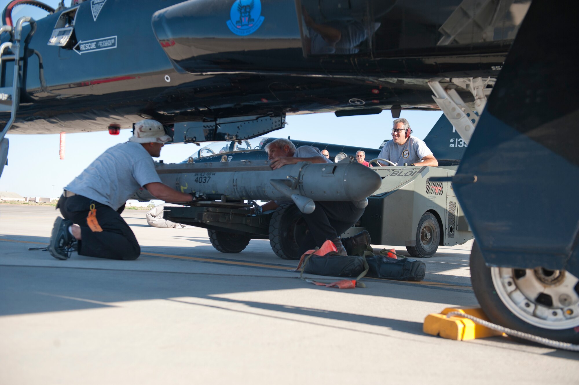 Raul Ceniceros, Ronald Legand, and Jeremy Hale, all M1 Support Services maintainers, attach a radar jammer pod onto a T-38 Talon at Holloman Air Force Base, N.M., Jun 4. For the first time, the T-38 has been modified to fit the ALQ-188 pod for use as a radar jammer. This newest addition to the T-38 will assist in its training mission by making it a more effective adversary for the F-22 Raptor during simulated combat exercises. (U.S. Air Force photo by Airman 1st Class Daniel E. Liddicoet/Released)

