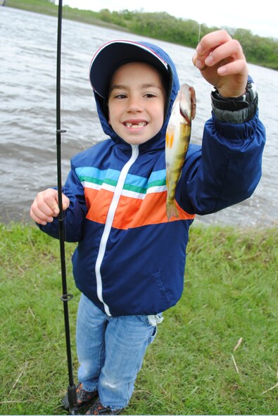 Eight-year-old Mason Kosofsky proudly holds a yellow perch he reeled in during the 25th Annual Kid’s Fishing Derby on June 1, 2013, at Larimore Dam, N.D.  The derby was youngster’s first time fishing. (U.S. Air Force photo/Staff Sgt. Luis Loza Gutierrez)
