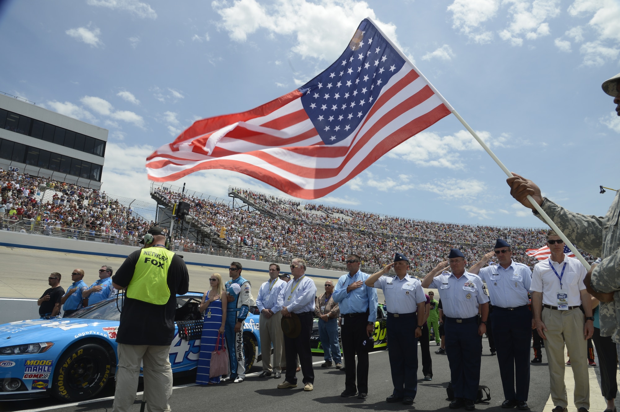 Members of the 314th Recruiting Squadron stand at attention beside the crew of Aric Almirola, driver of the No. 43 Smithfield Foods/U.S. Air Force Ford during the National Anthem before the start of the Fed Ex 400 Benefiting Autism Speaks at Dover International Speedway in Dover, Del. The Air Force uses race weekend as a major recruiting tool for potential future Airmen. (U.S. Air Force photo/Greg L. Davis)