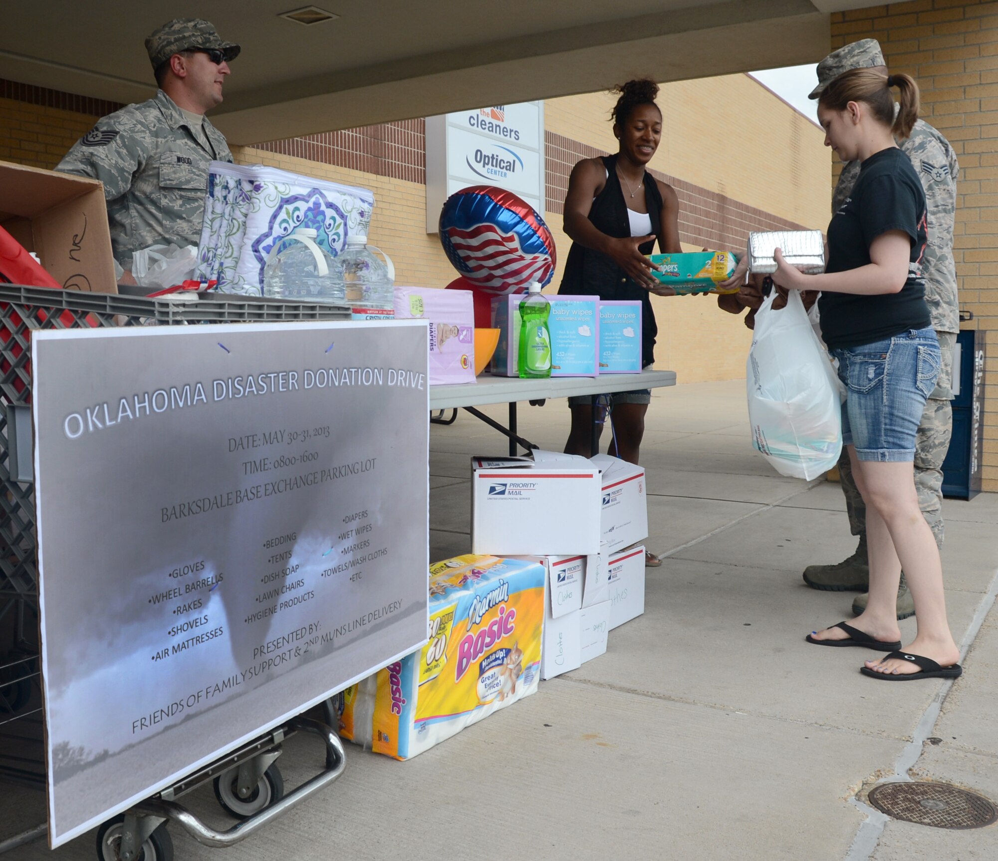 Senior Airman Benjamin Wilkes, 2nd Aircraft Maintenance Squadron, and his wife Alisha, right, give donations to Senior Airman Shaun Williams, 707th Maintenance Squadron, for the Oklahoma Disaster Donation Drive being held at the Exchange on Barksdale Air Force Base, La., May 30, 2013. The 2nd Munitions Squadron line delivery section is working with Friends of Family Support at the Airman and Family Readiness Center to gather supplies to send for relief of the victims of the recent tornadoes in Oklahoma. The supplies included shovels, beddings, tents, hygiene products, diapers and towels among others. (U.S. Air Force photo/Staff Sgt. Amber Corcoran)