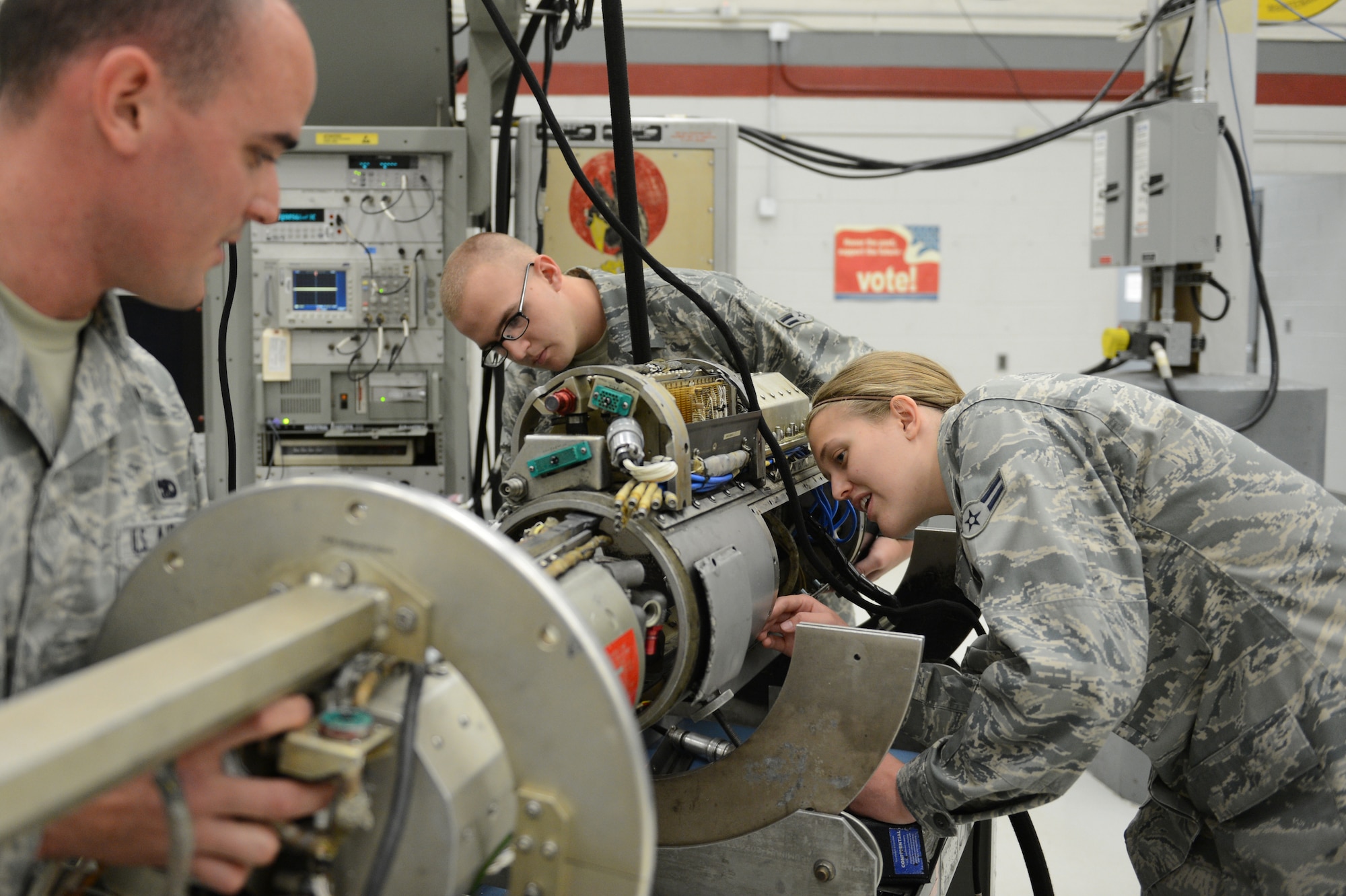 U.S. Air Force Senior Airman Poll Duran, Airman 1st Class Hannah Kreun and Airman 1st Class Bradley Boatman, all 20th Component Maintenance Squadron electronic warfare team members, examine a cold plate and its shell which is a section of the 184 Electronic Attack Pods, at Shaw Air Force Base, May 16, 2013. The pods are used in combat to jam radars and the cold plates cool and power the pod. (U.S. Air Force photo by Airman 1st Class Krystal M. Jeffers/Released)