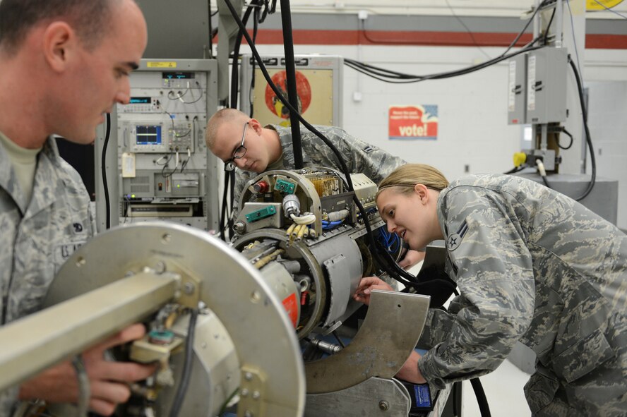 U.S. Air Force Senior Airman Poll Duran, Airman 1st Class Hannah Kreun and Airman 1st Class Bradley Boatman, all 20th Component Maintenance Squadron electronic warfare team members, examine a cold plate and its shell which is a section of the 184 Electronic Attack Pods, at Shaw Air Force Base, May 16, 2013. The pods are used in combat to jam radars and the cold plates cool and power the pod. (U.S. Air Force photo by Airman 1st Class Krystal M. Jeffers/Released)