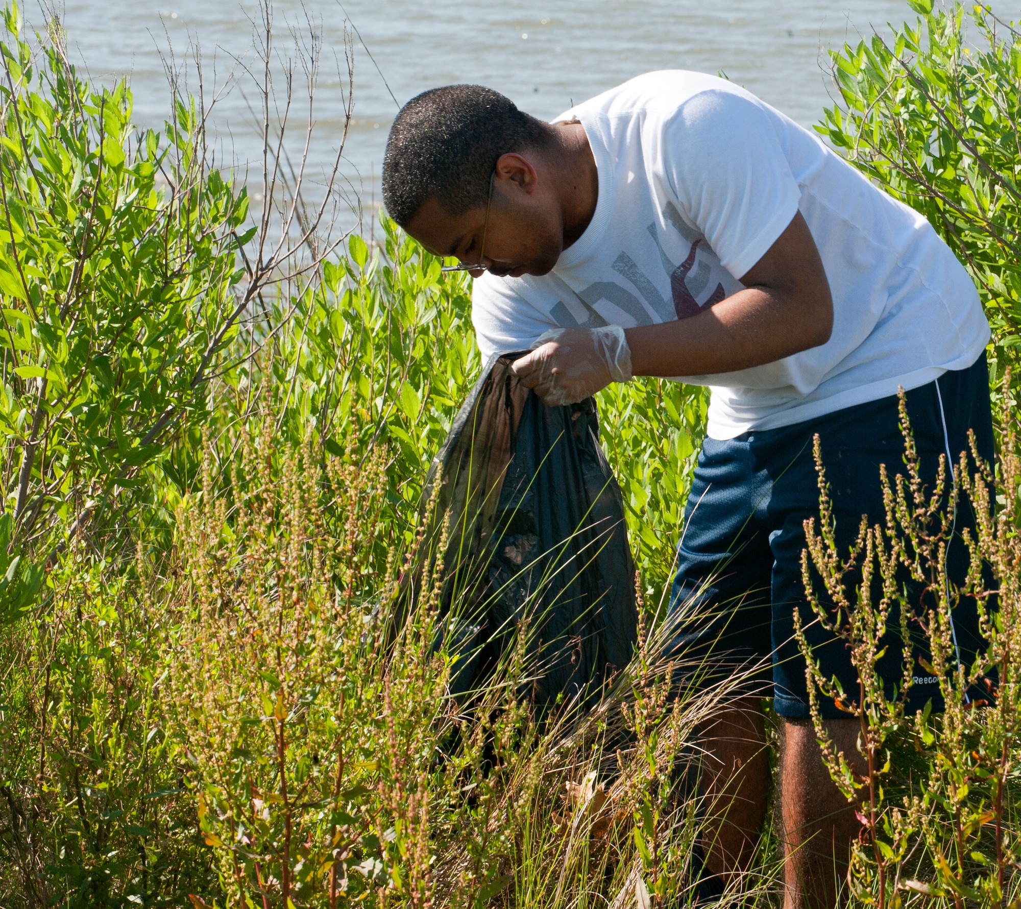U.S. Air Force Senior Airman Joseph Johnson, 438th Supply Chain Operations Squadron materiel management technician, picks up trash during Clean the Bay Day at Langley Air Force Base, Va., June 1, 2013. Johnson was one of the 217 Langley volunteers who participated in the event. (U.S. Air Force photo by Airman 1st Class Kimberly Nagle/Released) 