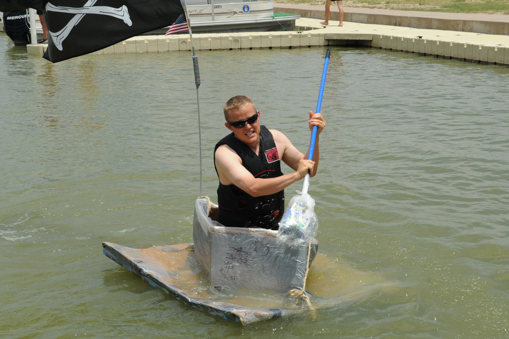 GOODFELLOW AIR FORCE BASE, Texas -- Navy Chief Petty Officer Joshua Roundy, Navy Center for Information Dominance Detachment, paddles to the dock during the Build a Boat contest at the Goodfellow Recreation Camp, May 27. Roundy won first place in the individual category. (U.S. Air Force photo/ Staff Sgt. Laura R. McFarlane)