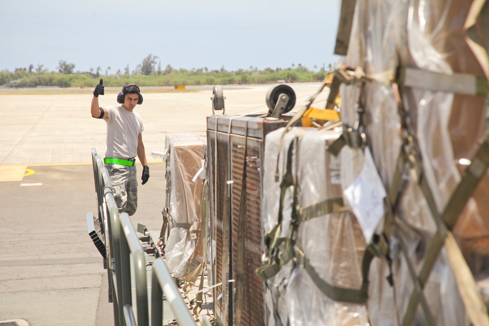 38th Aerial Port Squadron cargo transportation specialist Airman Leonardo Vargas gives the thumbs up to his crew members as they prepare to offload cargo from a 60K loader today on the highline dock at the Joint Base Pearl Harbor-Hickam air freight terminal. (U.S. Air Force photo by Staff Sgt. Rashard Coaxum/released)