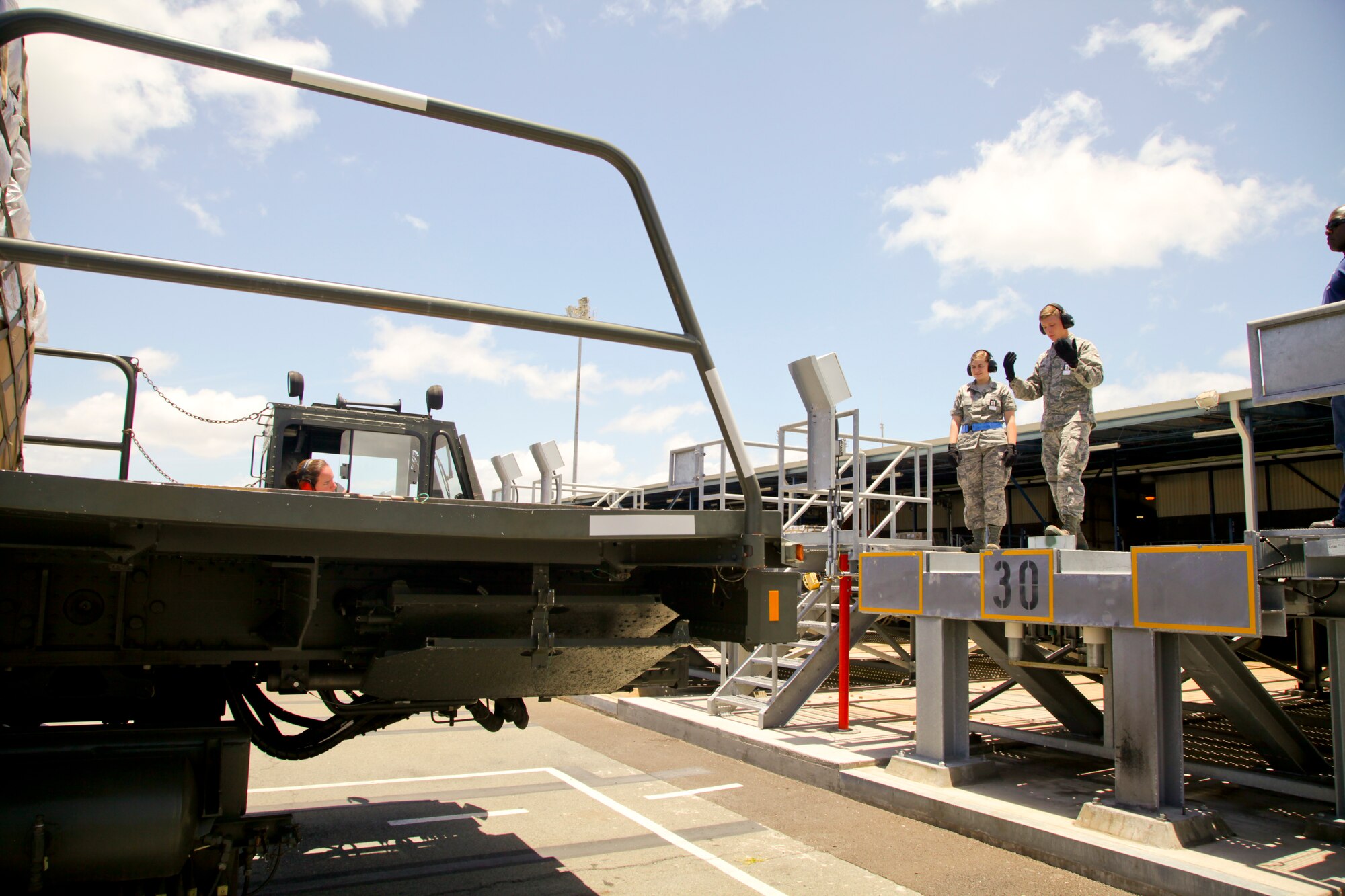 38th Aerial Port Squadron cargo transportation specialist Airman Jeremy Kitzmann marshals in a 60K loader into position today at the highline dock at the air freight terminal here at Joint Base Pearl Harbor-Hickam. (U.S. Air Force photo by Staff Sgt. Rashard Coaxum/released)