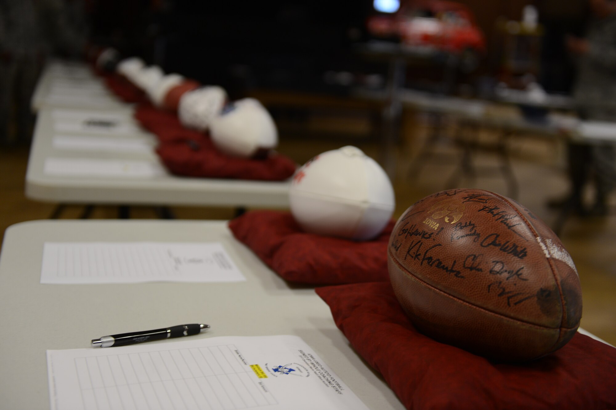 SPANGDAHLEM AIR BASE, Germany – A row of footballs signed by professional athletes rest in a line during a silent auction at the Brick House May 31, 2013. More than 500 requests for donations reached national sports stars and team coaches to support Operation Warm Heart. (U.S. Air Force photo by Airman 1st Class Gustavo Castillo/Released)