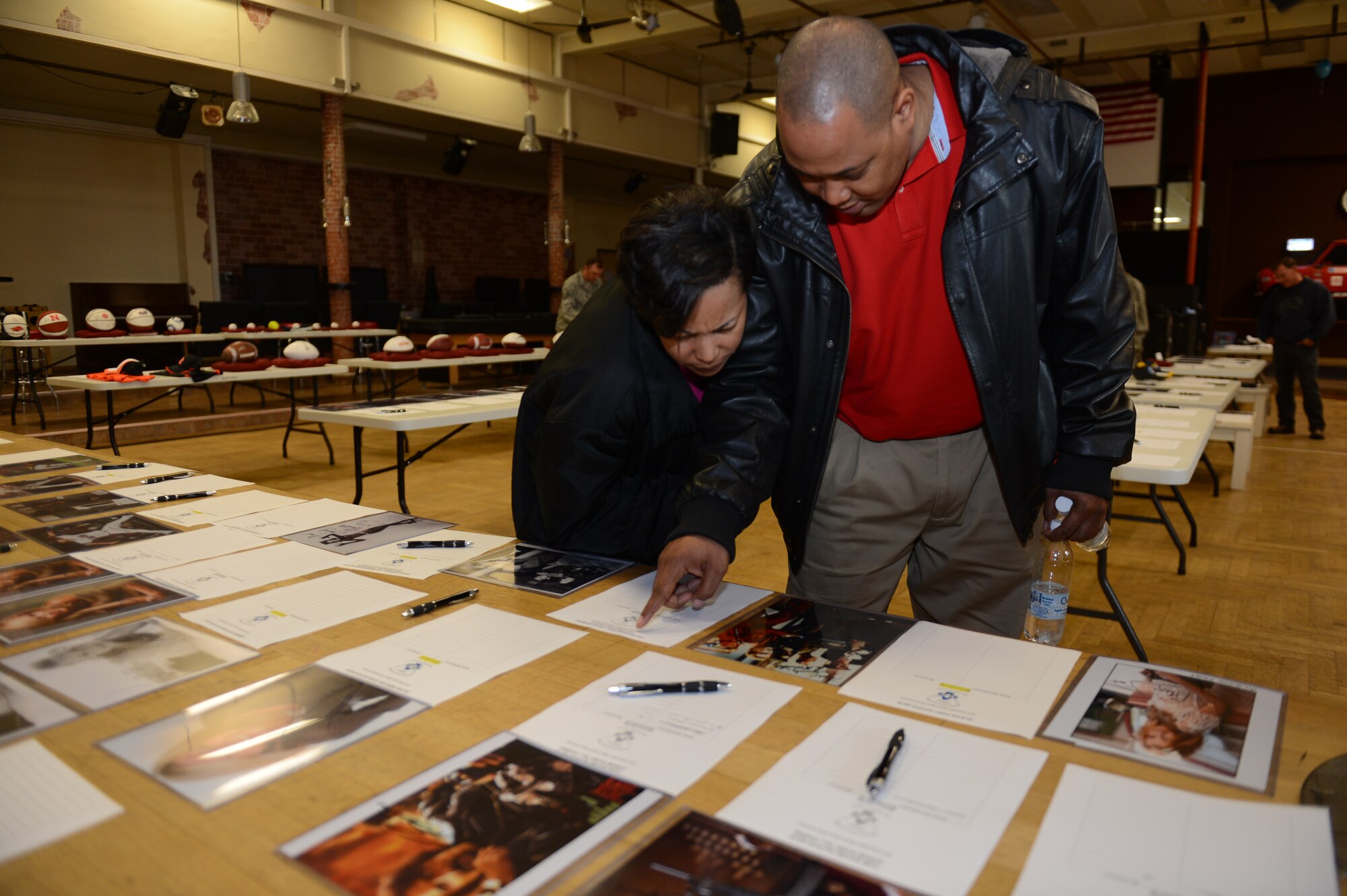 SPANGDAHLEM AIR BASE, Germany – Tyrone Parker, 52nd Force Support Squadron work life specialist from Birmingham, Ala., and Silvia Parker from Simmesport, La., look at autographed photos of movie and television stars during a silent auction for Operation Warm Heart at the Brick House May 31, 2013. The auction was made up of autographed memorabilia from sports franchises, authors and entertainment celebrities. (U.S. Air Force photo by Airman 1st Class Gustavo Castillo/Released)