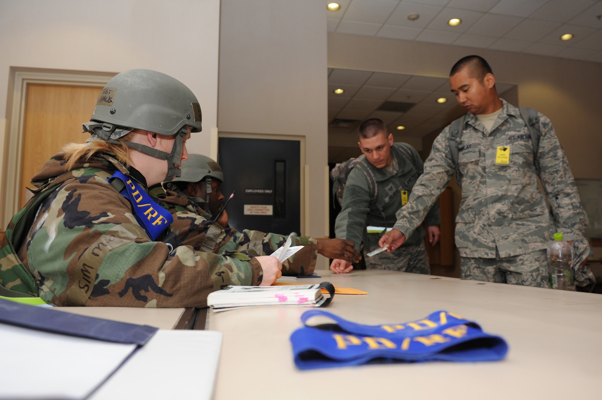Tech. Sgt. Judell Haug and Staff Sgt. Brandon Andrews, 8th Force Support Squadron personnel deployment reception function members, take identification cards from 8th Fighter Wing role-players during exercise Beverly Bearcat 13-01 at Kunsan Air Base, Republic of Korea, April 8, 2013. The 8th FSS PDRF members were inspected on their ability to properly process inbound personnel to the base. (U.S. Air Force photo by Staff Sgt. Jonathan Fowler/Released)