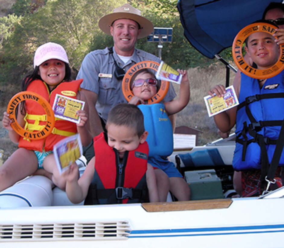 Park ranger Adam Thompson presents young boaters with "You've Been Caught Being Good" ice cream vouchers for wearing their life jackets as their families prepare to launch their boat at Pine Flat Lake, the U.S. Army Corps of Engineers Sacramento District park near Piedra, Calif. (U.S. Army photo by Marian Picher /Released)