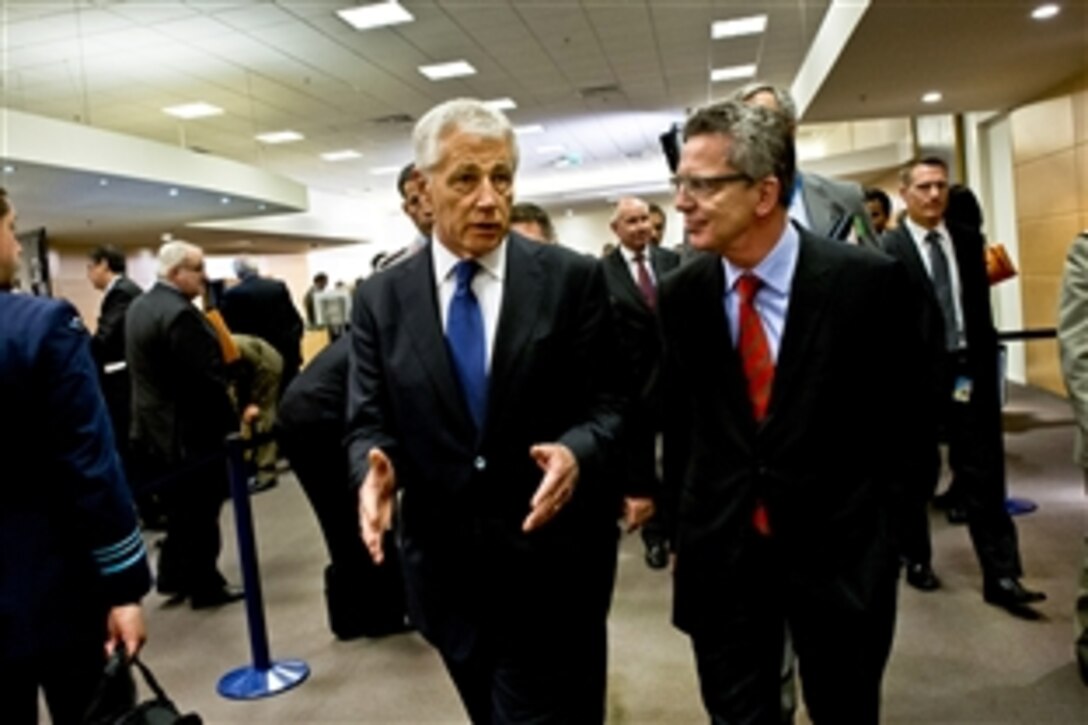U.S. Defense Secretary Chuck Hagel, left, stops for a brief meeting with German Defense Minister Thomas de Maiziere during a NATO session in Brussels, June 4, 2013. 