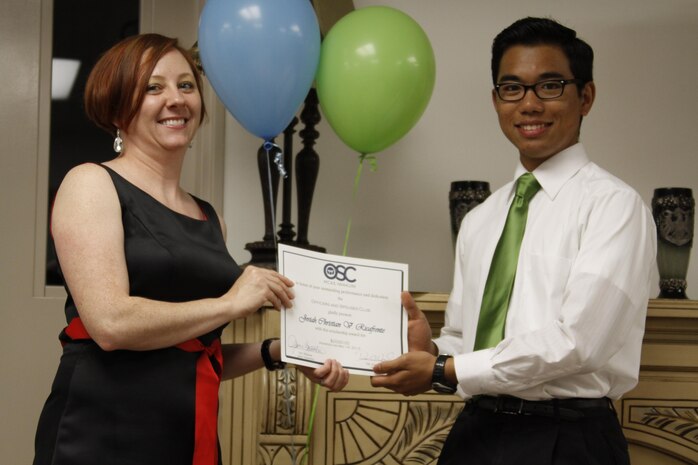 Deanna O'Neal, left, Officers' Spouses' Club philanthropy chairman, hands Josiah Ricafrente, Matthew C. Perry High School senior, his scholarship at the Officers' Spouses' Club scholarship night held in building 1200 at Marine Corps Air Station Iwakuni, Japan, May 16, 2013. Ricafrente said he plans to use his money toward paying for his tuition at the University of California at Irvine as he pursues his studies toward becoming an aerospace engineer.