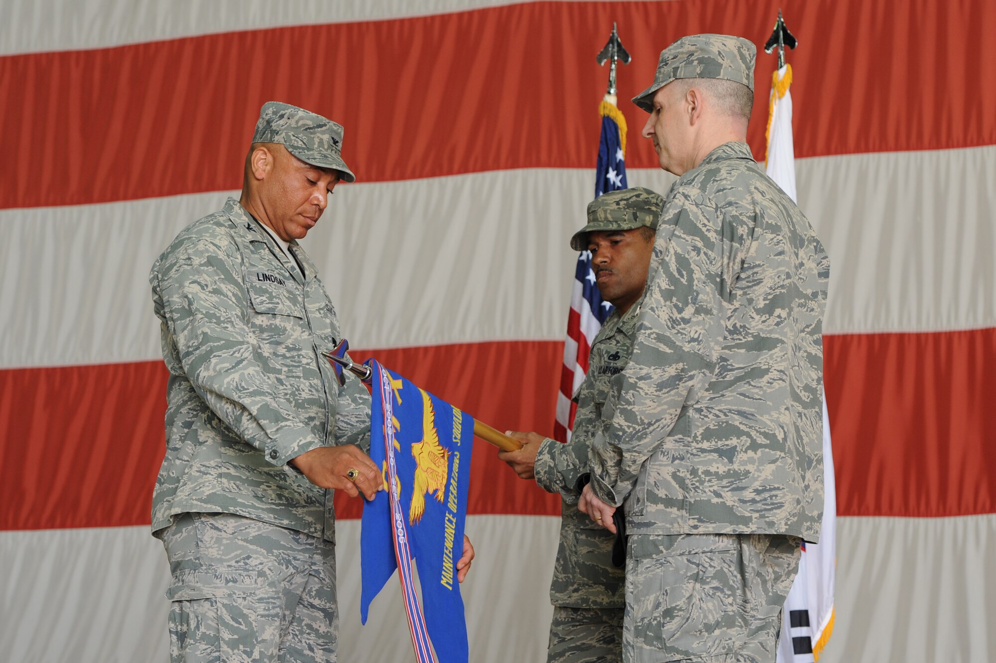 Col. Ray Lindsay, 8th Maintenance Group commander, furls the guidon while Maj. John Groff, 8th Maintenance Operations Squadron, watches during the 8th MOS deactivation ceremony at Kunsan Air Base, Republic of Korea, May 31, 2013. Furling and encasing the guidon is a traditional part of an Air Force deactivation ceremony. (U.S. Air Force photo by Staff Sgt. Jonathan Fowler/Released)