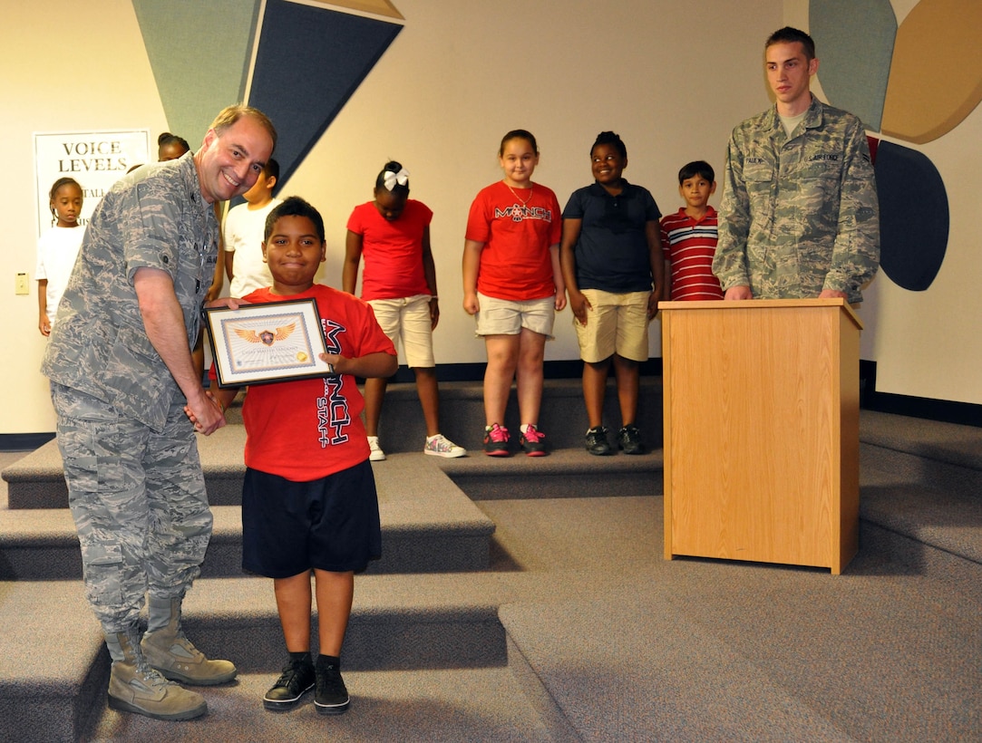 NORTH LAS VEGAS, Nev. -- (Far left) Col. David Rosso, 99th Medical Group chief of medical staff, congratulates student, Geovanny Lopez, on achieving the rank of chief master sergeant in Manch Elementary School’s Thunderbird Reading Program on May 23. Ceremony narrator Airman First Class David Paulk (far right), 99th MDG, headed an effort that brought 45 Nellis and Creech AFB Airmen to the school from March through May to read to the students as a way to help the kids with their reading skills. In order to be promoted, the students had to read a certain number of books and take a comprehension test on each of them. Lopez was also a graduate of STARBASE NELLIS, an academy hosted by the 926th Group that orients students with science, technology, engineering and mathematics careers. (U.S. Air Force photo/Maj. Jessica Martin)