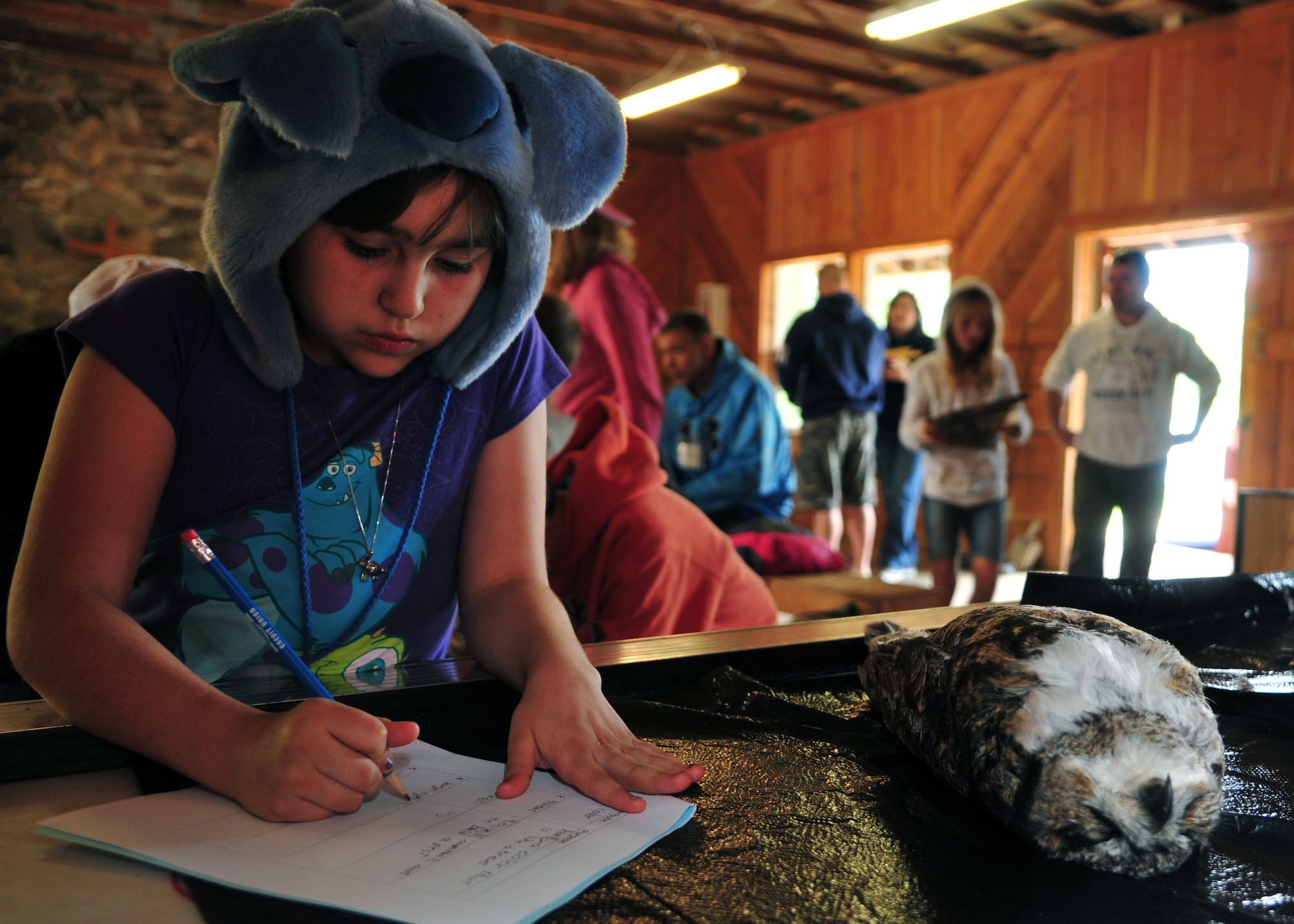 Carrilyn, a fourth grader from Michael Anderson Elementary School, writes down facts about the horned owl, which is found in many parts of the world during the science session May 30, 2013, at Michael Anderson Elementary School’s annual overnight camping trip at YMCA Camp Reed. Students learned what habitats certain animals live in, why they have certain attributes such as the horned owls’ sharp claws, which are used to grab prey as it swoops down. (U.S. Air Force photo by Senior Airman Earlandez Young/Released)   