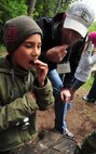 Chief Master Sgt. Lance Turner, superintendent of the 92nd Medical Group and camp counselor, comforts Andrew, a fourth grader, by eating a piece of a slug with him during the wilderness survival session, which was taught by Fairchild survival specialists May 30, 2013, at YMCA Camp Reed. Michael Anderson fourth grade class made its annual trip to Camp Reed for an overnight campout. (U.S. Air Force photo by Senior Airman Earlandez Young/Released)