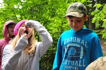 Lilli, a fourth grader from Michael Anderson Elementary School, prepares to sample a slug after learning what insects are safe to eat from Fairchild survival specialists while Sawyer, a fourth grader, tries to decide if he wants to taste an insect during the wilderness survival session May 30, 2013, at YMCA Camp Reed. Students had the opportunity to sample other insects such as beetles, worms and a species of flowering plant in the lily family called queen’s cup. (U.S. Air Force photo by Senior Airman Earlandez Young/Released)   