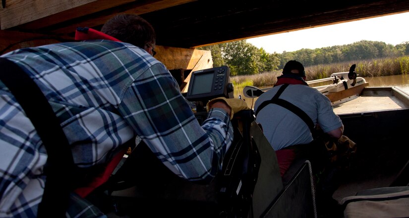 James Dolan, 733rd Civil Engineer Division environmental flight conservationist, ducks before driving his boat beneath a low bridge leading to a training area at Fort Eustis, Va., June 4, 2013. The platform sites are close to important training areas for Fort Eustis, making the mission of discovering nutria paramount to mission success. (U.S. Air Force photo by Airman 1st Class Austin Harvill/Released)