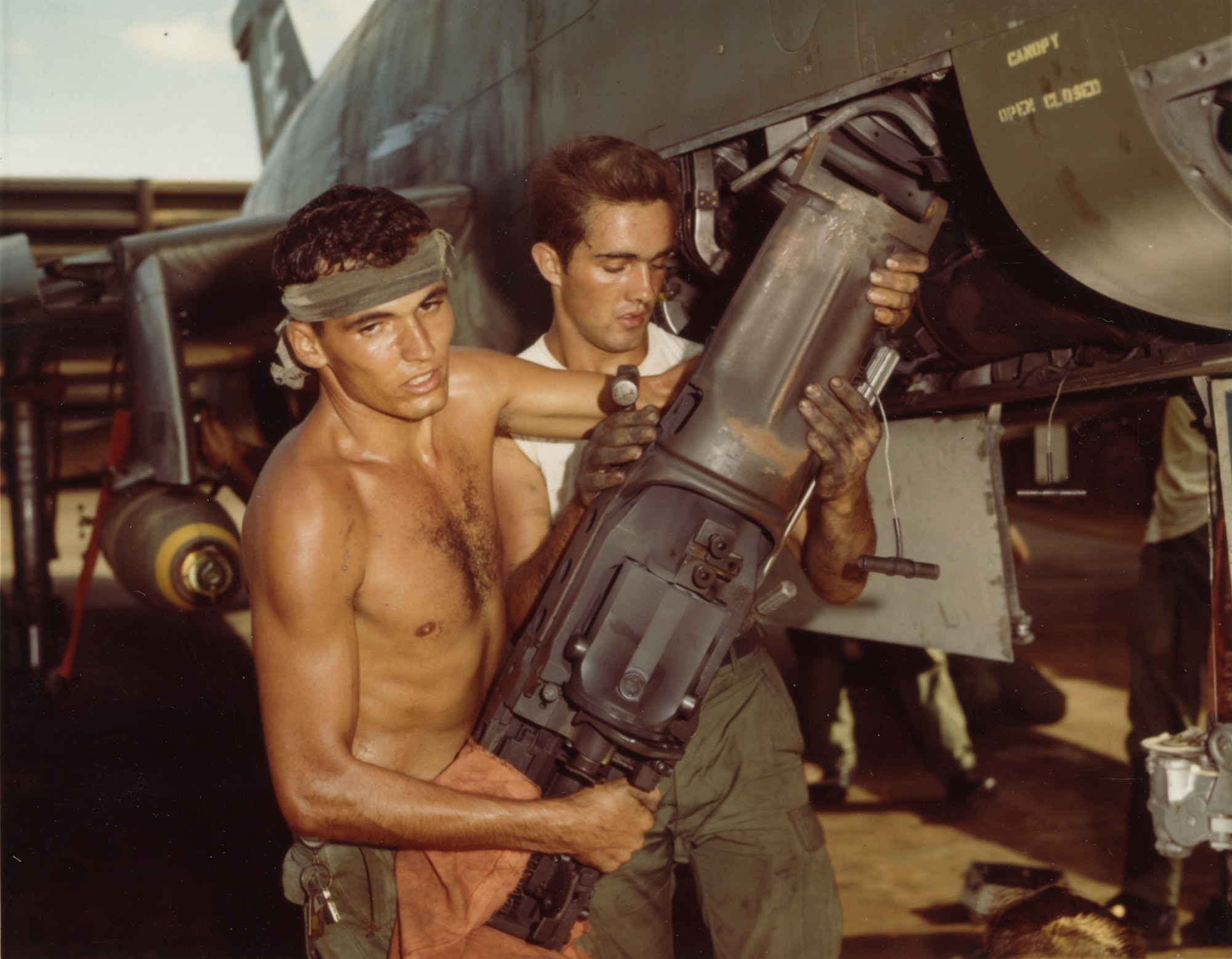 On the hot flight line at Phu Cat Air Base, Airmen 2nd Class Francis Branch (left) and John Sellung remove a 20mm cannon from an F-100 in October 1967. (U.S. Air Force photo)