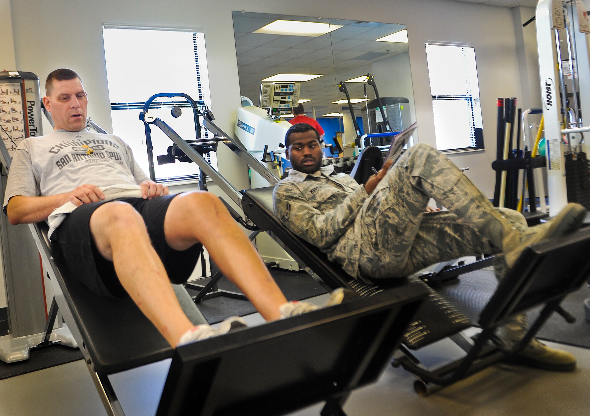 U.S. Air Force Master Sgt. David Desjardin, training management section chief for 1st Special Operations Maintenance Operations Squadron (left), gets assistance from Airman 1st Class Jakarrious Marshall, a physical therapy technician for 1st Special Operations Medical Operations Squadron, with leg presses during physical training on Hurlburt Field, Fla., May 29, 2013. On average, technicians see 25 to 30 patients on a daily basis. (U.S. Air Force photo/Airman 1st Class Christopher Callaway) 