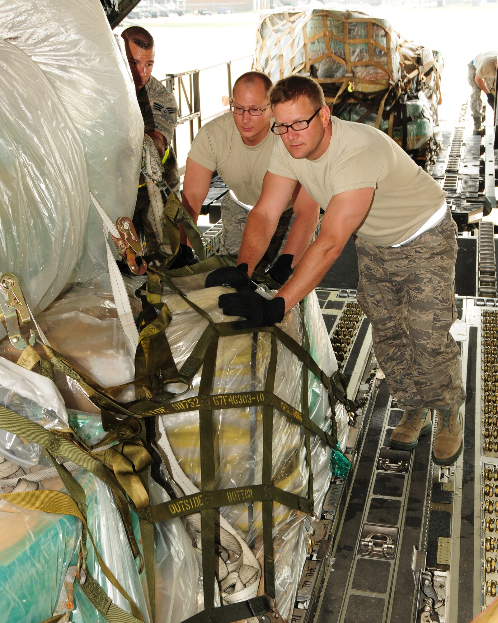 (Left to right) Senior Airman Francesco Torcasio, 30th Aerial Port Squadron ramp specialist, Tech. Sgt. Patrick Williamson,30 APS ATOC specialist, and Senior Airman Gary Tredo, 30 APS cargo specialist, position a pallet onboard a 452nd Air Mobility Wing C-17 at the Niagara Falls Air Reserve Station, N.Y. on May 29, 2013. The pallet of locally donated civilian firefighting equipment along with ten other pallets and an ambulance were part of a Denton Cargo training flight bound for the Dominican Republic. (U.S. Air Force photo by Peter Borys)