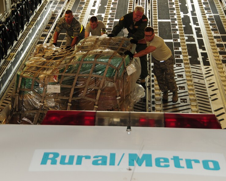 (Left to right) Senior Airman Francesco Torcasio, 30th Aerial Port Squadron ramp specialist, Master Sgt. Michael Peppers,30 APS load planner, Master Sgt. Christopher Whittey,  452nd Air Mobility Wing loadmaster, and Senior Airman Gary Tredo, 30 APS cargo specialist, push a pallet onboard a 452nd C-17 at the Niagara Falls Air Reserve Station, N.Y. on May 29, 2013. The pallet of locally donated civilian firefighting equipment along with ten other pallets and an ambulance were part of a Denton Cargo training flight bound for the Dominican Republic. (U.S. Air Force photo by Peter Borys)