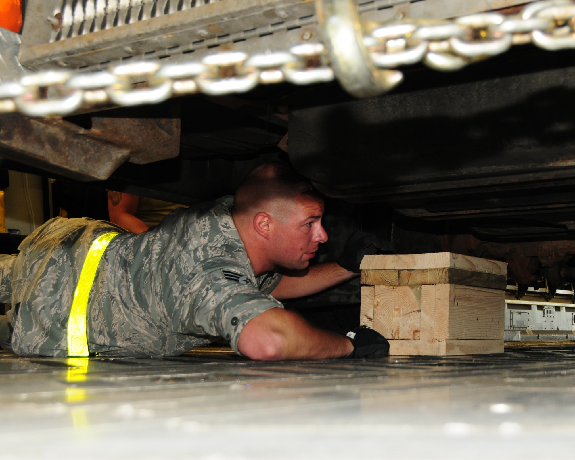 Senior Airman Francesco Torcasio, 30th Aerial Port Squadron ramp specialist, positions “sleeper shoring” underneath an ambulance onboard a 452nd AMW C-17 at the Niagara Falls Air Reserve Station, N.Y. May 29, 2013. The device was used to help minimize or prevent the donated local ambulance from bouncing during flight.  The vehicle and eleven pallets of locally donated firefighting equipment were part of a Denton Cargo training flight bound for the Dominican Republic. (U.S. Air Force photo by Peter Borys)