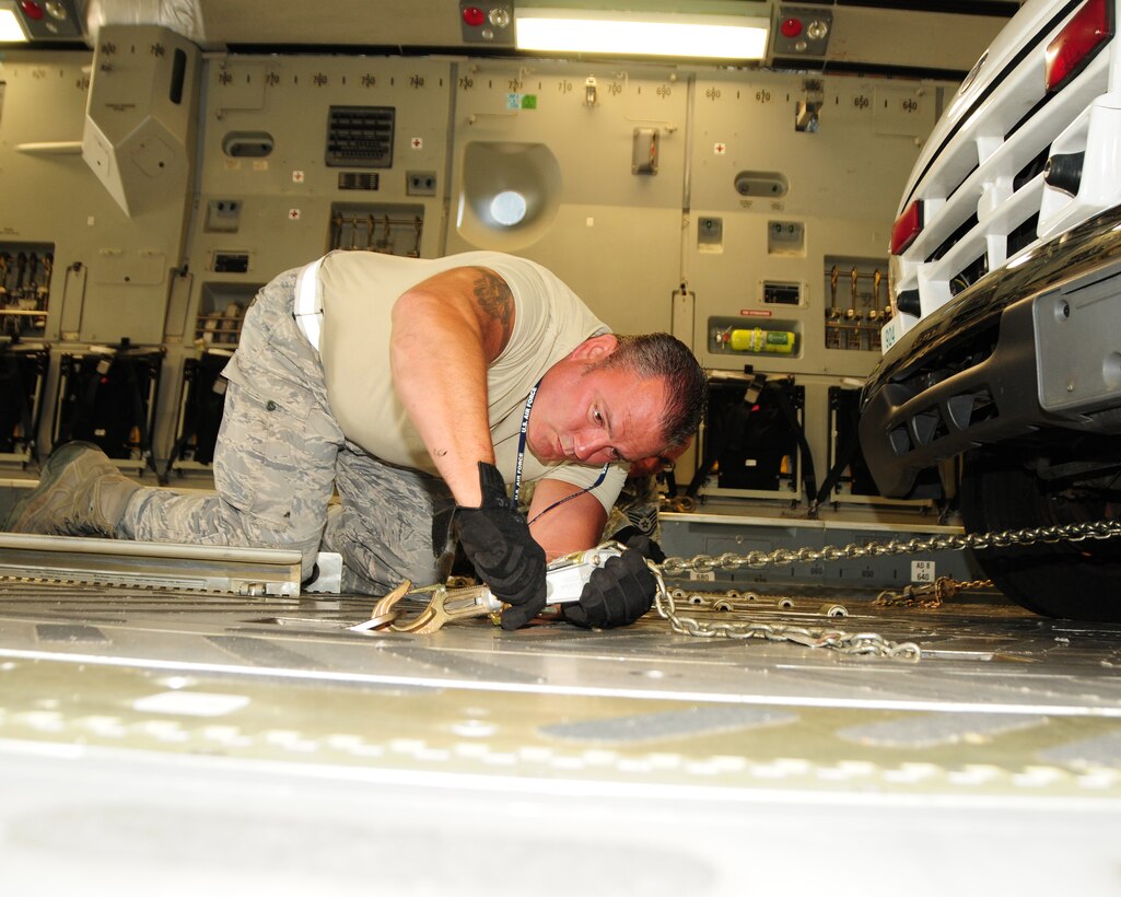 Tech. Sgt. Jack Meara, 30th Aerial Port Squadron air transportation operations center specialist, applies chains to the floor of a 452nd AMW C-17 for forward restraint on a locally donated ambulance at the Niagara Falls Air Reserve Station, N.Y. May 29, 2013. Chains and other devices were used to insure the vehicle did not move in any direction. The ambulance and eleven pallets of locally donated civilian firefighting equipment were part of a Denton Cargo training flight bound for the Dominican Republic. (U.S. Air Force photo by Peter Borys)
