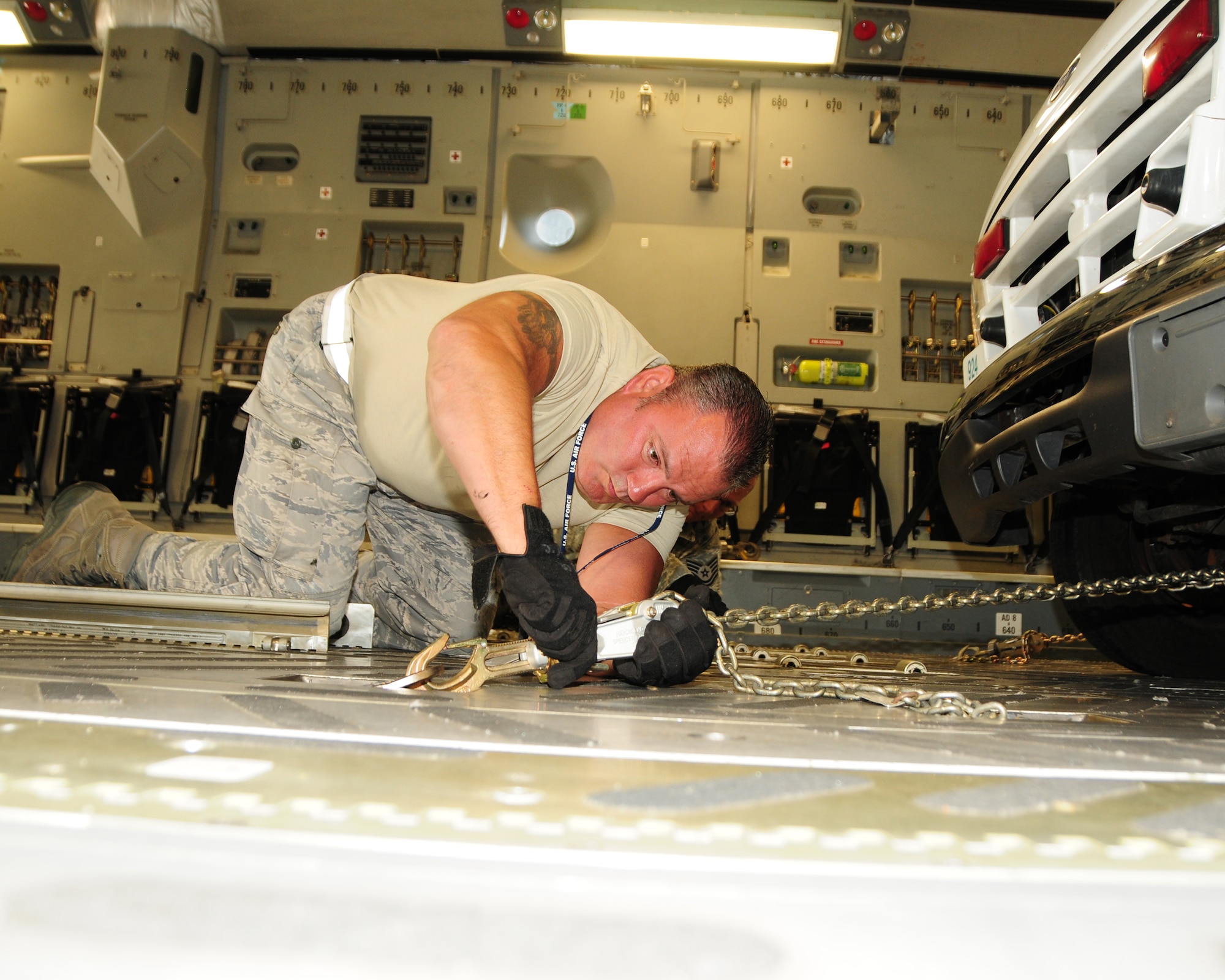 Tech. Sgt. Jack Meara, 30th Aerial Port Squadron air transportation operations center specialist, applies chains to the floor of a 452nd AMW C-17 for forward restraint on a locally donated ambulance at the Niagara Falls Air Reserve Station, N.Y. May 29, 2013. Chains and other devices were used to insure the vehicle did not move in any direction. The ambulance and eleven pallets of locally donated civilian firefighting equipment were part of a Denton Cargo training flight bound for the Dominican Republic. (U.S. Air Force photo by Peter Borys)