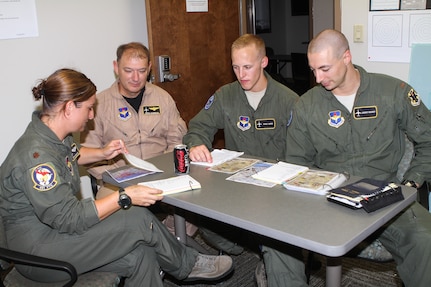 Maj. Carrie Register, Mr. Kevin Salonman and 2nd Lts. Chad James and Jeremy Mooney, all of the 451st Flying Training Squadron, debrief the mission of the first flight of the modified T-1 Jayhawk aircraft June 4, 2013 at Naval Air Station Pensacola, Fla. The aircraft has been modified for electronic warfare training, marking the first time in Air Force history that an undergraduate aviation program has formally incorporated the fundamentals of electronic warfare in flight into their syllabus.  (U.S. Air Force photo by Master Sgt. Michelle Alexander)