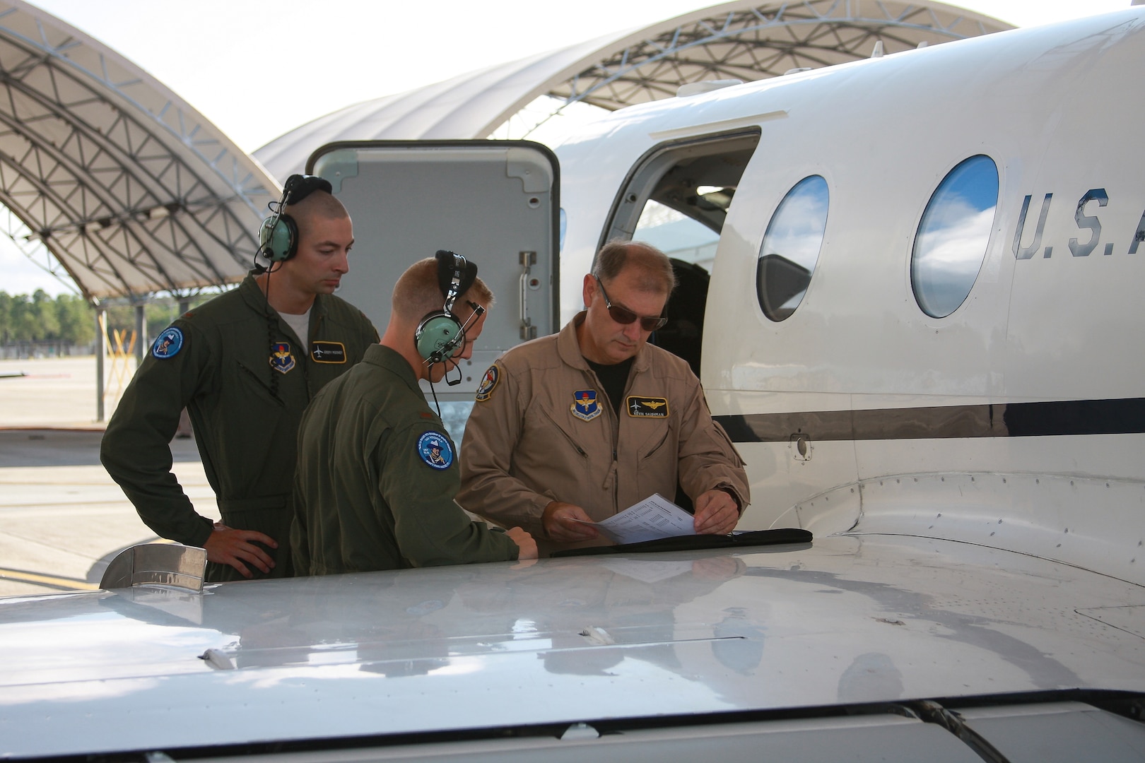 Second Lts. Jeremy Mooneyand Chad James, and Mr. Kevin Salonman, all of the 451st Flying Training Squadron, go over mission information prior to the first flight of the modified T-1 Jayhawk aircraft June 4, 2013 at Naval Air Station Pensacola, Fla. The aircraft has been modified for electronic warfare training, marking the first time in Air Force history that an undergraduate aviation program has formally incorporated the fundamentals of electronic warfare in flight into their syllabus.  (U.S. Air Force photo by Airman 1st Class Kailyn Cabrera)