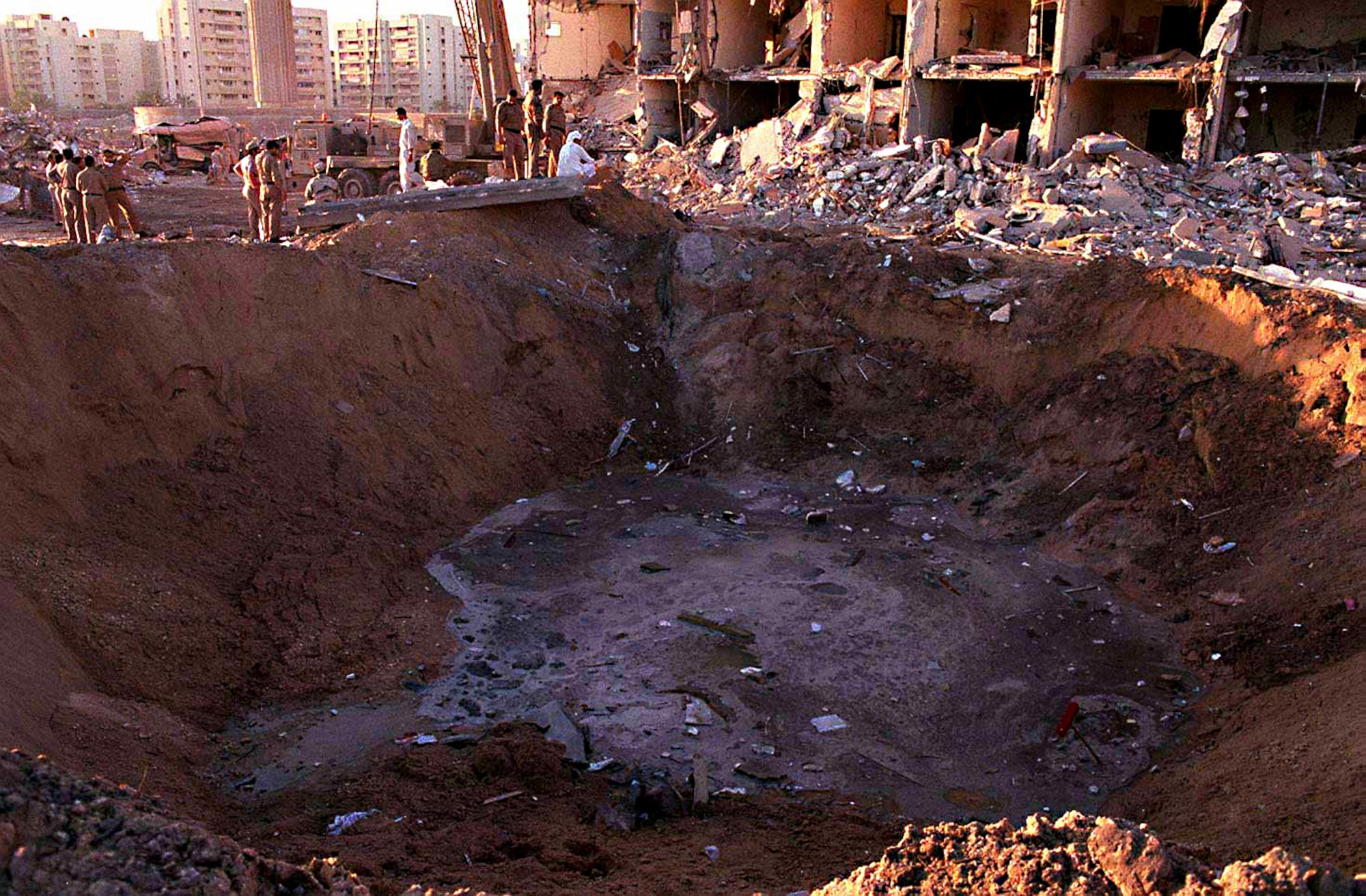 U.S. and Saudi military personnel peer into the crater caused by the explosion of a fuel truck outside the northern fence of Khobar Towers on King Abdul Aziz Air Base near Dhahran, Saudi Arabia, at 2:55 p.m. EDT, Tuesday, June 25, 1996. Several buildings were damaged and there were numerous U.S. casualties. The latest information from Dhahran indicates that 19 people are dead and 64 people are hospitalized. Additionally, over 200 have been treated for injuries and released. The facility houses U.S. service members and serves as the headquarters for the U.S. Air Force's 4404th Wing (Provisional), Southwest Asia. (DoD photo/Released)