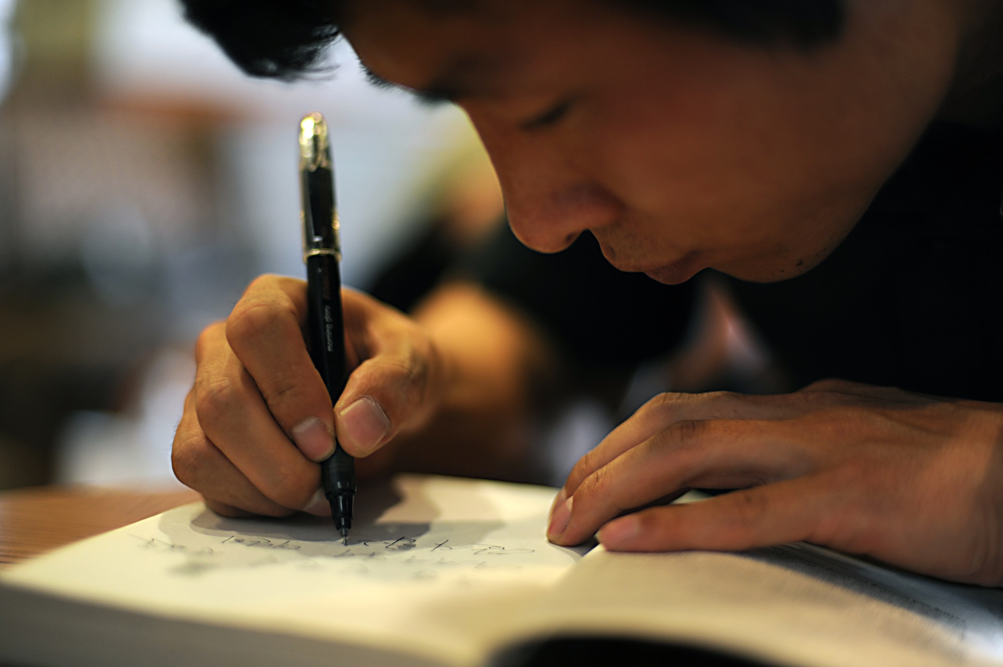 Kim Hyuk, North Korean defector and public speaker, signs a copy of “Nothing to Envy,” a book which features his story of living and escaping from North Korea, at Osan Air Base, Republic of Korea, May 31, 2013. Hyuk signed dozens of books for audience members who attend the three-part informative seminar where he told nearly 700 people his life story. (U.S. Air Force photo/Staff Sgt. Sara Csurilla)   