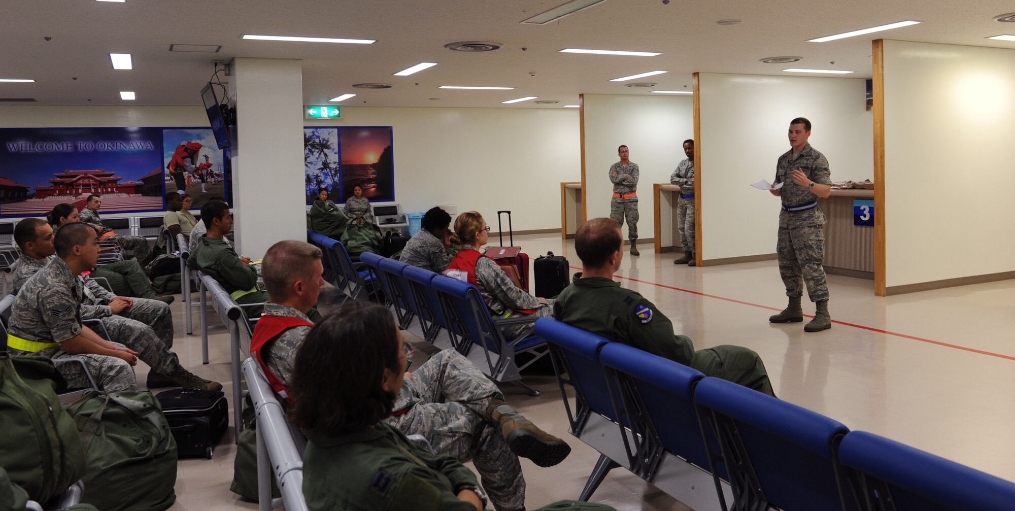 U.S. Air Force Airman 1st Class Todd Holly, 18th Wing Public Affairs broadcast journalist, gives the PA pre-deployment brief at a personnel deployment function line  during a training exercise on Kadena Air Base, Japan, June 3, 2013. PDF lines are used to ensure personnel have the necessary paperwork and equipment needed to deploy. (U.S. Air Force photo by Airman 1st Class Keith A. James/Released)