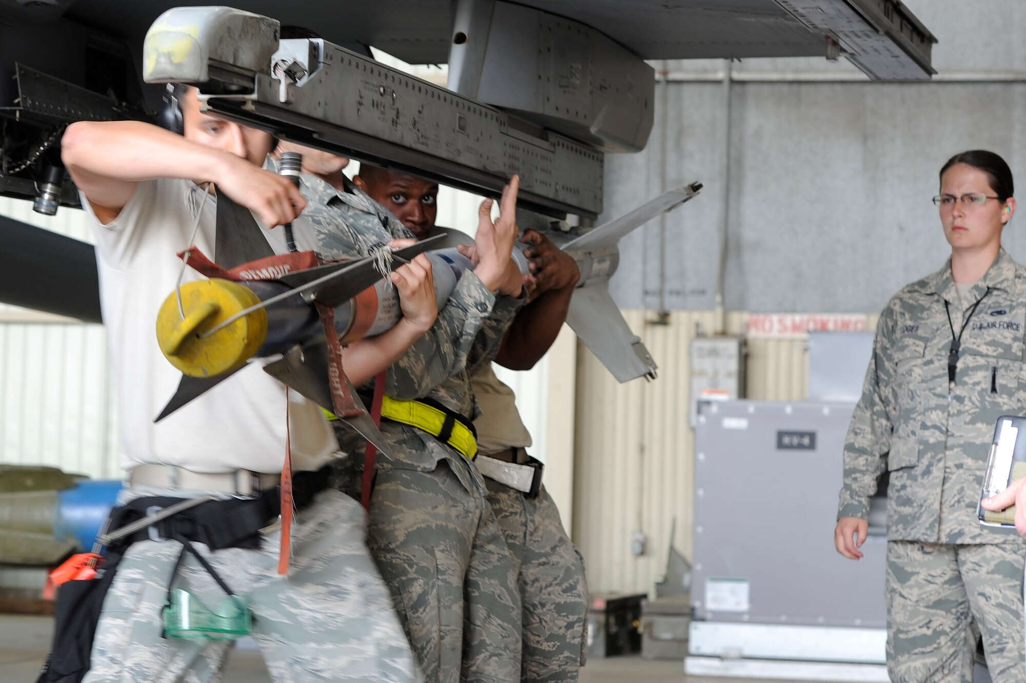 KUNSAN AIR BASE, Republic of Korea – 80th Aircraft Maintenance Unit crew chiefs, Senior Airman Enrique Melgarejo, left, Staff Sgt. Jonathan Oliver, middle, and Senior Airman Damon Bryant, load a AIM 9 L/M sidewinder, while Senior Airman Cecil Loges, 8th Maintenance Operations Squadron load barn weapons standardization inspector, watches during a load crew competition at Kunsan Air Base Republic of Korea, May 23, 2013. Teams were graded on a 100 point written test, members dress and appearance and a composite tool kit inspection (all tools present and properly marked) and any discrepancies were documented and deducted from the total score. (U.S. Air Force photo by Staff Sgt. Tong Duong/ Released) 