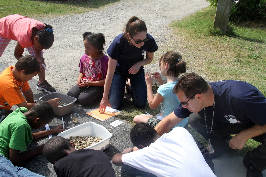 NORFOLK -- Norfolk District volunteers Rachael Haug and Gregg Williams help a group of students measure baby oysters.