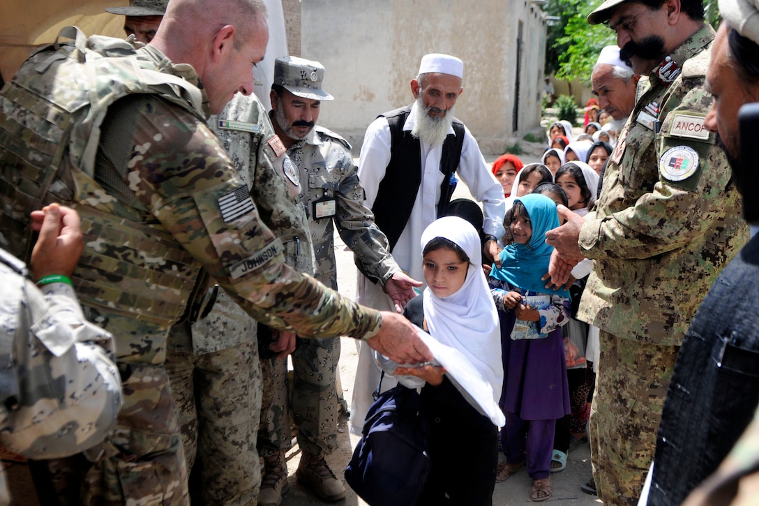 U.S. Army Col. Richard Johnson, left, and Afghan border police hand out school supplies to local Afghan school girls during a humanitarian aid mission in Jalalabad City in Afghanistan’s Nangarhar province, May 25, 2013. Johnson is commander of the 101st Airborne Division's 1st Brigade Combat Team, Female Engagement Team and Afghan Border Police Zone 1, Security Forces Advise and Assistance Team.
