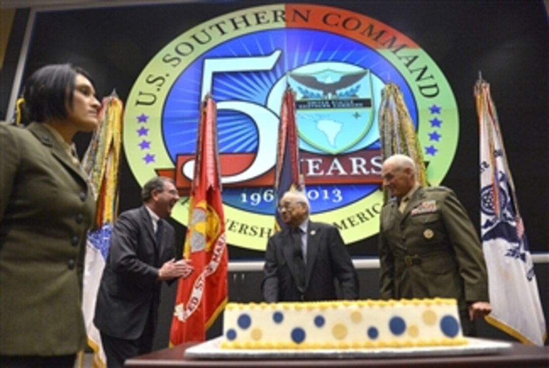 Deputy Secretary of Defense Ashton B. Carter, second from left, and Commander U.S. Southern Command Gen. John F. Kelly, right, share a light moment with Southern Command employee John Samson, center, who was offered the first slice of a cake cut to mark the 50th anniversary of the command during a ceremony in Miami, Fla., on June 4, 2013.  Samson received a letter of appreciation during the ceremony and has served over 50 years in government service with most of it at Southern Command.  