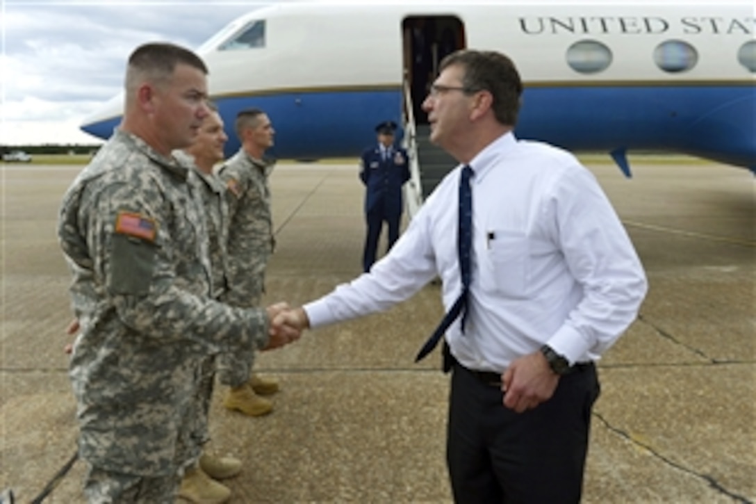 Deputy Defense Secretary Ash Carter, right, shakes hands with and coins service members before boarding his plane after visiting Fort Rucker, Ala., June 4, 2013.  