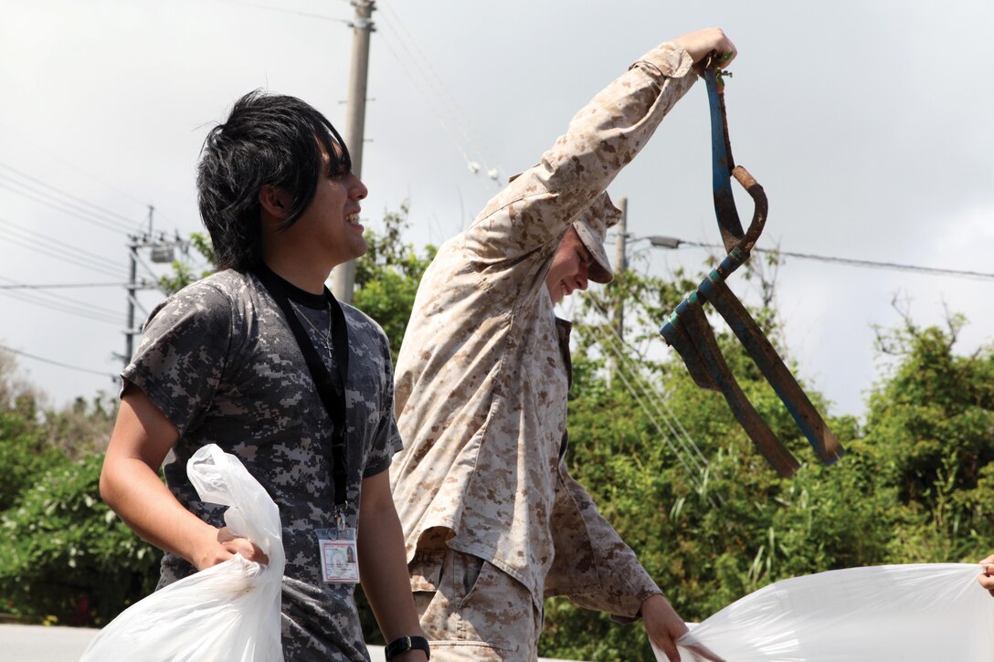Sgt. Coby L. Caldwell and Yoshihide Ikemiya break-down trash May 30 outside of Marine Corps Air Station Futenma’s Gate 1. Their cleanup efforts are part of “Okinawa 5.30 Go-Mi-Zero,” an islandwide campaign dedicated to beautifying Okinawa. Caldwell is a communications data chief with Headquarters and Headquarters Squadron, MCAS Futenma. Ikemiya is an intern with the office of government and external affairs for Marine Corps Base Camp Smedley D. Butler. Photo by Lance Cpl. Natalie M. Rostran