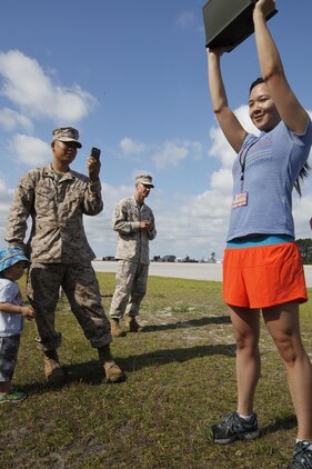 Rosemary Hong, wife of Sgt. Scott K. Yonemura, a satellite operator with MWCS-28, performs ammo can lifts while her family cheers her on. 