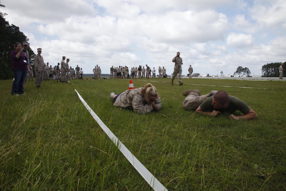 Lance Cpl. John Armistead, a refrigeration and air conditioning technician with Marine Wing Communications Squadron 28, low crawls beside his wife, Samantha, during the combat fitness test portion of Jane Wayne Day May 30. 