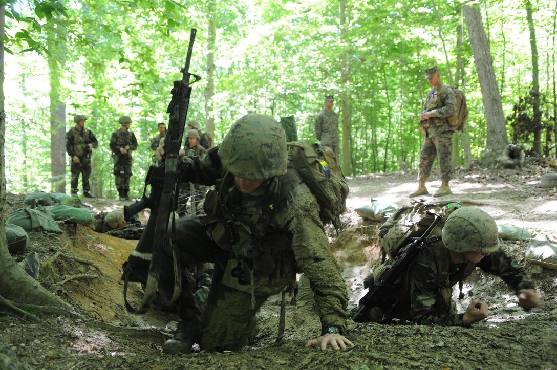 Naval Academy midshipmen drag themselves through the mud under barbed wire on the endurance course May 31, at the start of Leatherneck. The training replaces Officer Candidates School, introducing the midshipmen to Marine Corps requirements and whittling down their numbers.