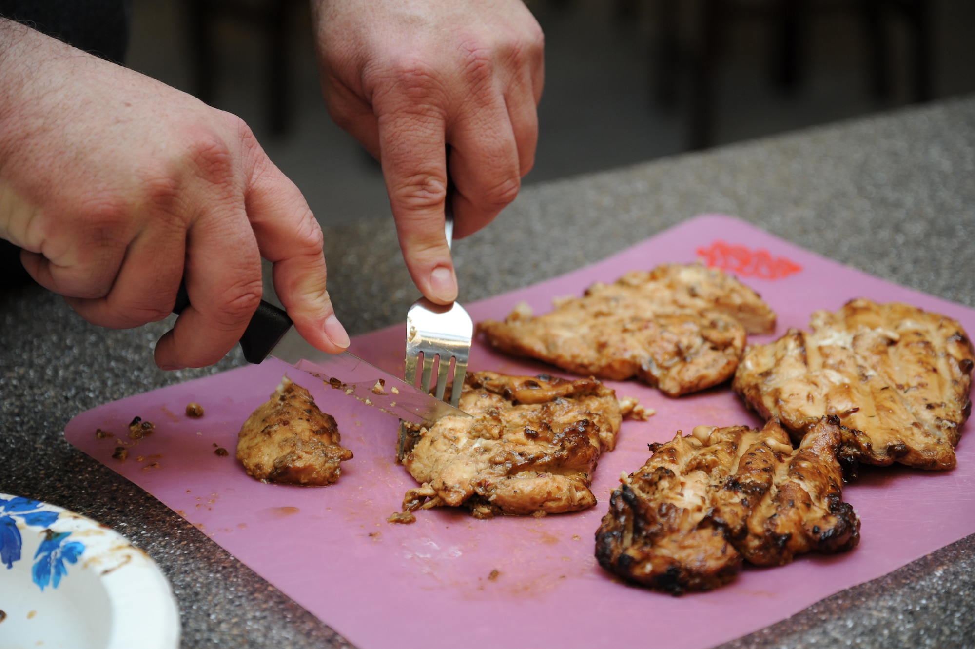 Tech. Sgt. (ret.) Chris Herron, a former tanker crew chief cuts through grilled chicken during the Health and Wellness Center's healthy cooking class.(U.S. Air Force photo by 2nd. Lt. Rachelle Smith/Released)