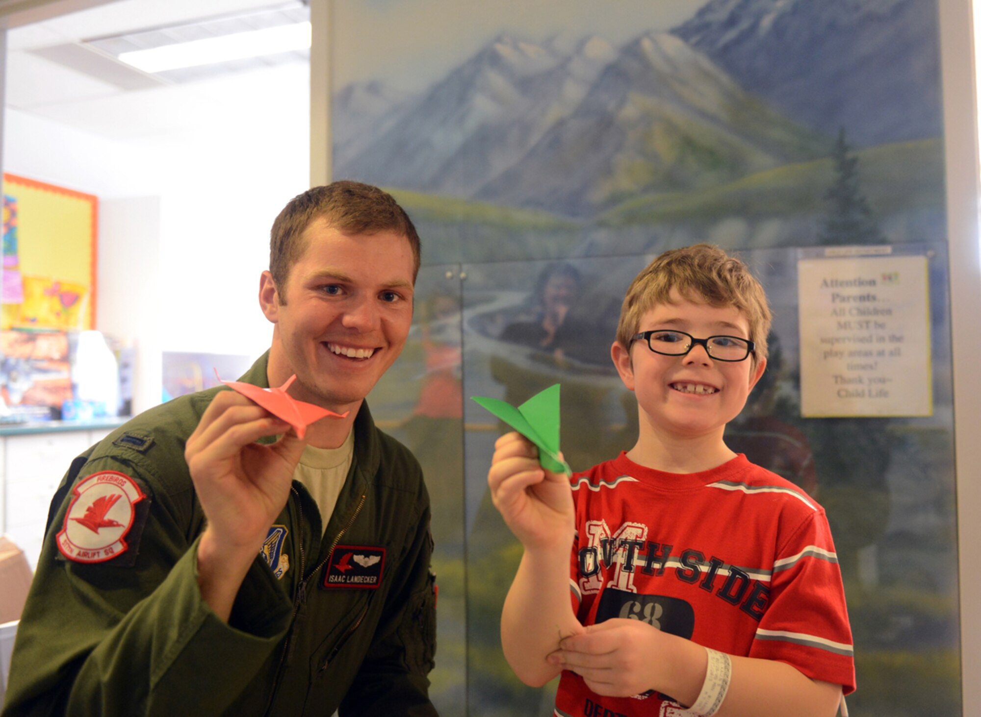 JOINT BASE ELMENDORF-RICHARDSON, Alaska -- Air Force 1st Lt. Isaac Landecker, 517th Airlift Squadron pilot, and Kagen LaBrie hold the paper airplanes they created during the 517th AS?s visit to Providence Children's Hospital May 22. Providence Children's Hospital has the only pediatric clinic in Alaska and serves children from all over state. (U.S. Air Force photo/Airman Ty-Rico Lea)