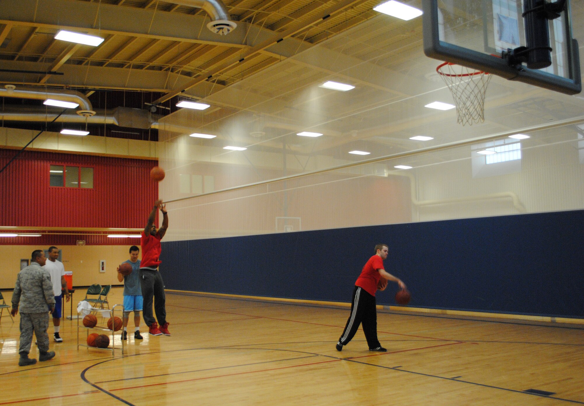 Staff Sgt. Michael Jordan, 341st Force Support Squadron fitness specialist, shoots a basketball as part of the 3-point shootout as others watch during the Health and Wellness Fair on May 29.  Volleyball, 3-on-3 basketball, a two-person relay, and sit-up and pushup contests were also held during the event to promote physical activity.  (U.S. Air Force photo/Senior Airman Cortney Paxton) 