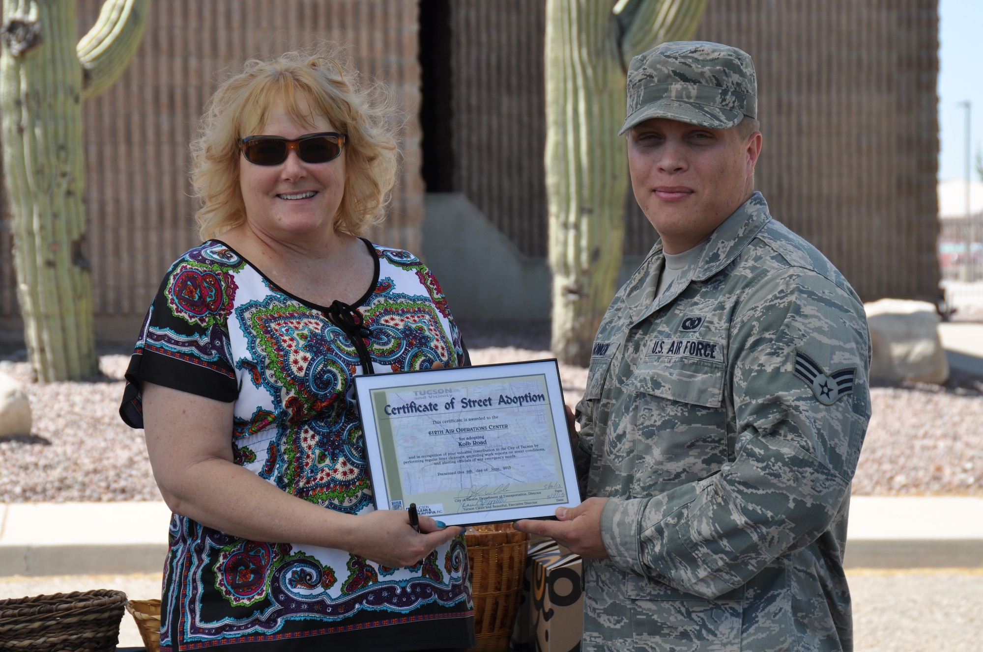 Jean Hickman, Adopt-a-Park coordinator for Tucson Clean & Beautiful, presents Senior Airman Benjamin Honken, 612th Air and Space Operations Center, with a certificate of recognition during a ceremony recognizing his units’ contributions to Tucson’s Adopt-a-Street program, June 6. (USAF photo by Master Sgt. Kelly Ogden/Released)