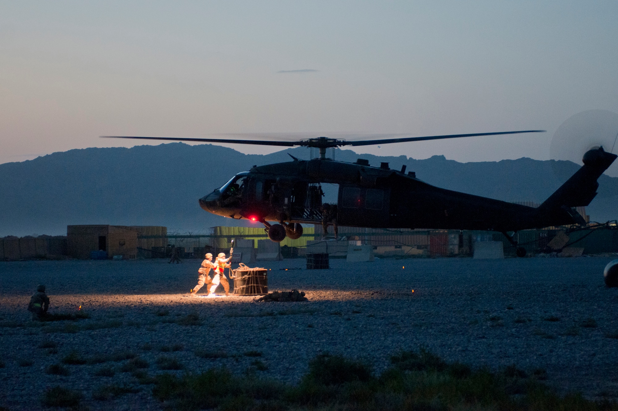 U.S. Air Force Tech. Sgt. Sean Buck and Airman 1st Class Pedro Cahua, both with the 451st Expeditionary Aircraft Maintenance Squadron, prepare to hook a 1,800 pound A-22 cargo bag to an approaching UH-60 Black Hawk helicopter flown by Soldiers of the 3rd Combat Aviation Brigade during a joint-coalition sling load training mission at Kandahar Airfield, Afghanistan, June 1, 2013. The training provided coalition members the opportunity to learn the concepts of illuminating a landing zone as well as in-flight cargo sling loading. (U.S. Air Force photo/Capt. Brian Maguire)