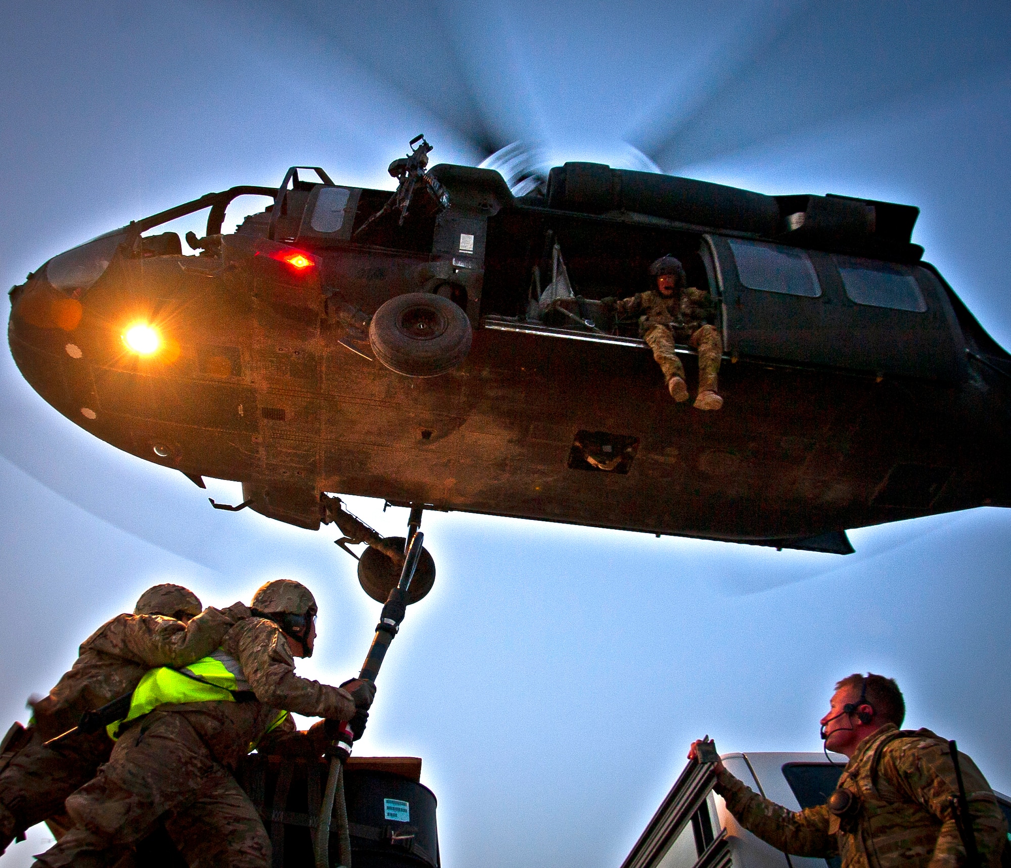 U.S. Air Force Capt. Christopher Kaighen braces Tech. Sgt. Michael Docodcil, both with the 451st Expeditionary Logistics Readiness Squadron, as they hook a 1,800 pound A-22 cargo bag to a UH-60 Black Hawk helicopter flown by Soldiers of the 3rd Combat Aviation Brigade during a joint-coalition sling load training mission at Kandahar Airfield, Afghanistan, June 1, 2013. U.S. Army Staff Sgt. Jacob Bishop (right), pathfinder with the 603rd Aviation Support Battalion, supervises the loading while U.S. Army Spc. Tyler Burriss, Task Force Knighthawk crew chief, 2-3 General Support Aviation Battalion, monitors from above. (U.S. Air Force photo/Senior Airman Scott Saldukas)